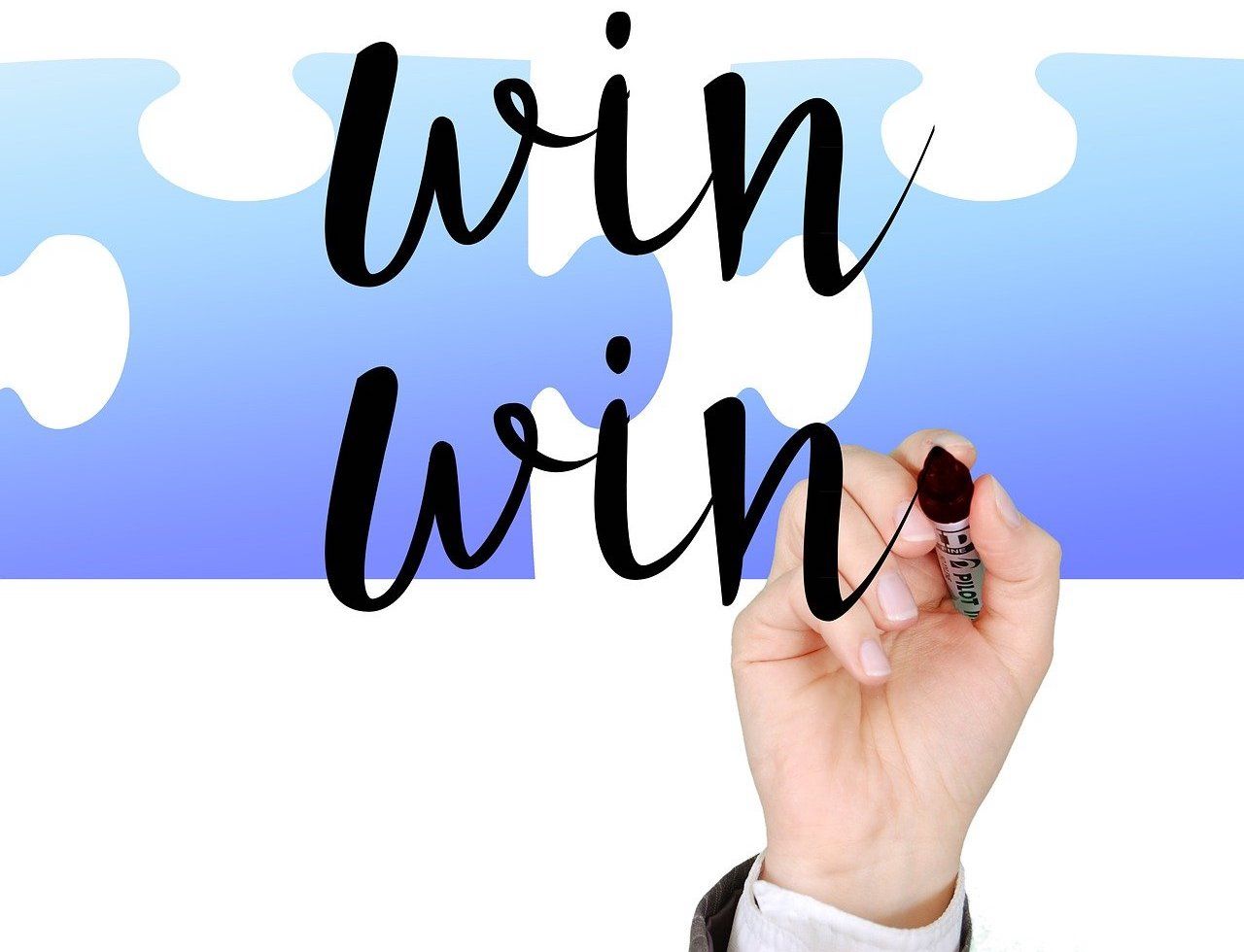 Hand writing win win on glass over blue puzzle pieces background.